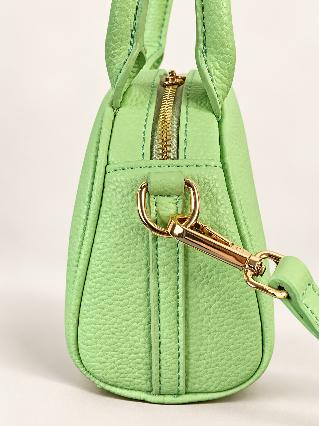 Side view of NORIVE Garden lime green mini handbag highlighting textured material, detailed stitching, gold-tone zipper, and detachable strap hardware.