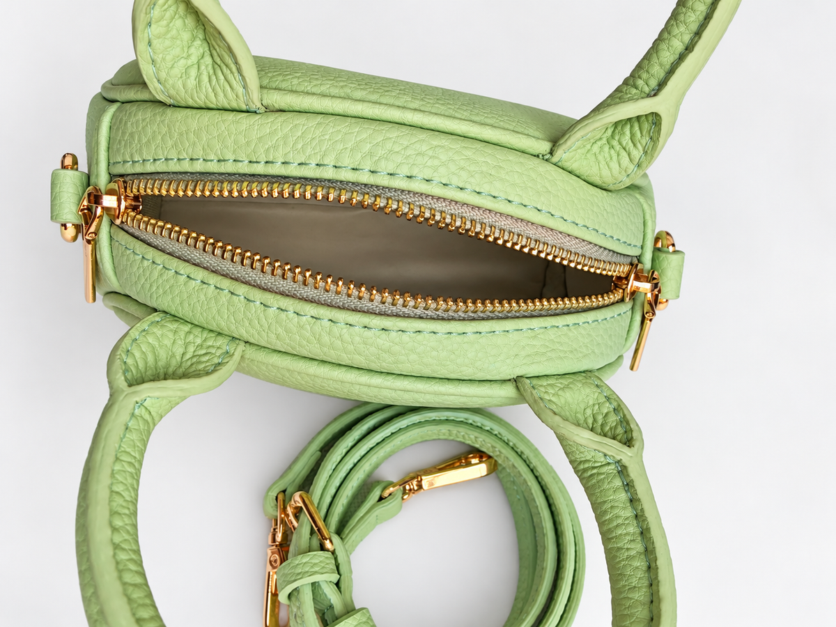 Top view of NORIVE Garden lime green mini handbag showing its open gold-tone zipper, compact interior, textured exterior, and rounded handles.